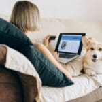 A woman reviewing website analytics on her laptop alongside her dog, working with an eCommerce consultant to boost online sales.
